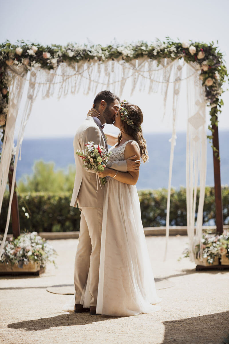 Beso de novios bajo el decorado del altar