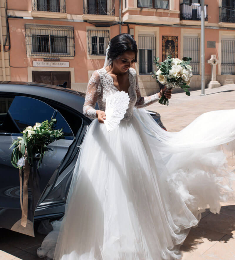 Bride getting out of bridal car with hand fan